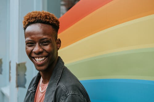 Free Positive young black guy laughing near graffiti wall with rainbow flag Stock Photo