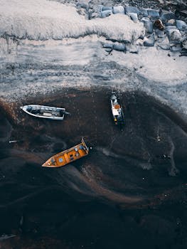 A stunning aerial view capturing boats resting on a dark sandy shoreline. Perfect for travel and nature themes.