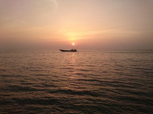 Silhouette of a Boat Sailing during Sunset