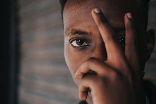 Free Thoughtful young black guy touching face and looking at camera Stock Photo