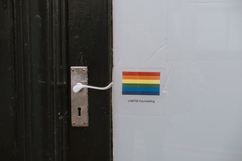 Free Colorful LGBTQ symbol of lesbian gay bisexual and transgender pride on wall near door knob on black door of counselling building Stock Photo