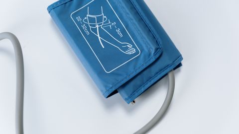 Close-up of a blue blood pressure cuff on a white surface, medical equipment for health monitoring.