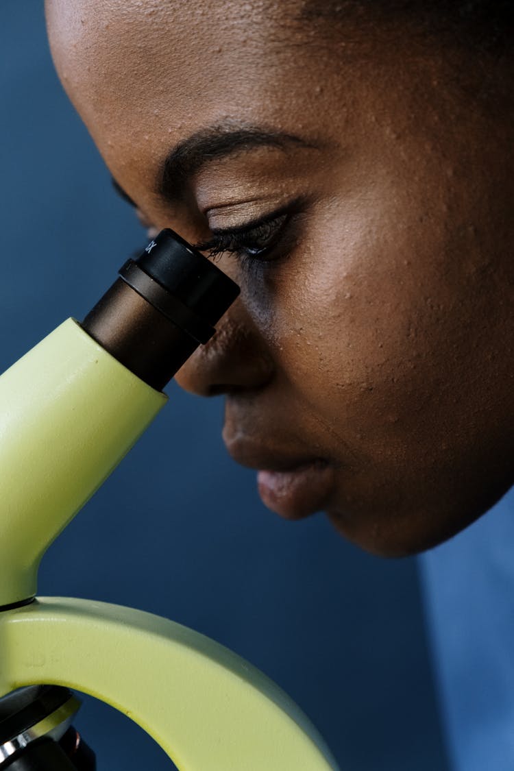 A Woman Looking Through A Microscope