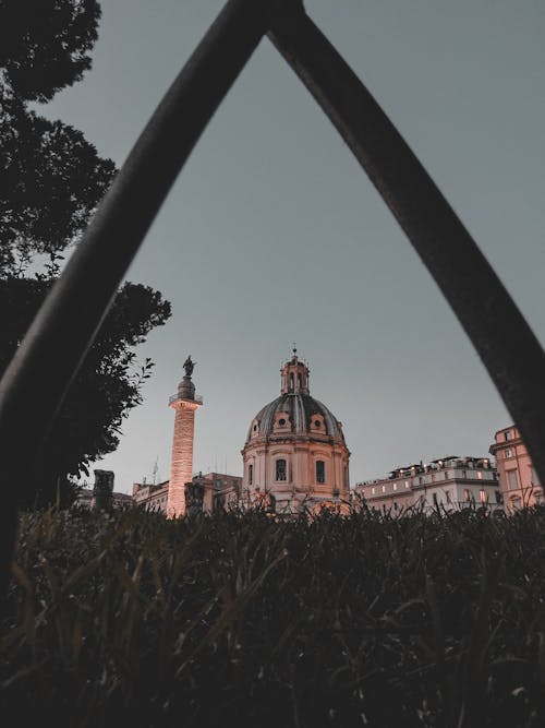 Low angle of domed Catholic cathedral near high spire with statue on top located in old European city