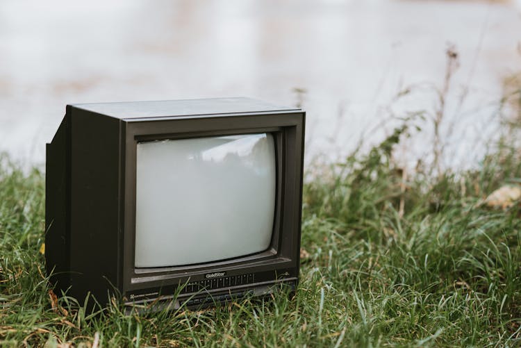 Retro TV Set On Grass Near Lake