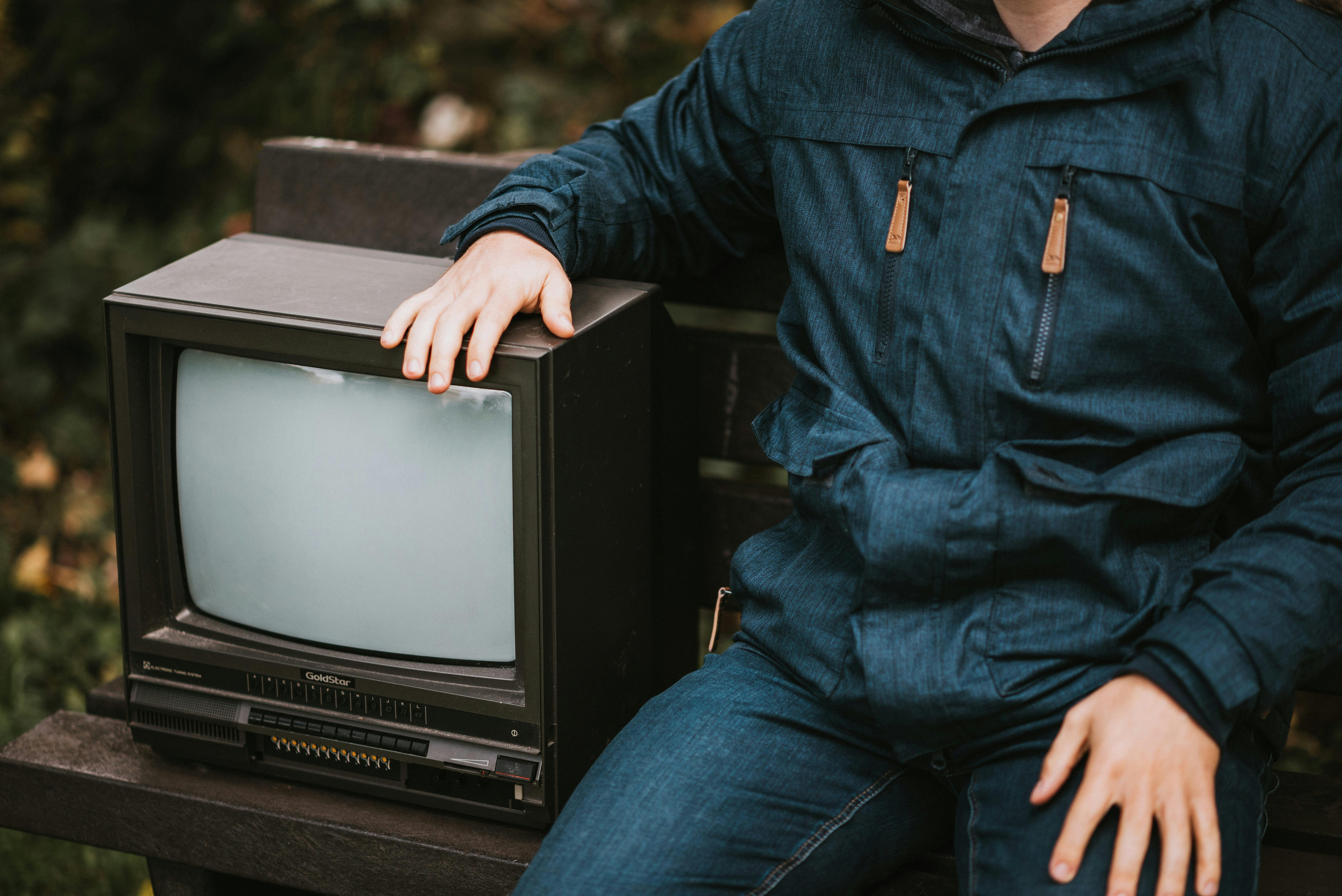 crop man sitting on bench with retro tv set