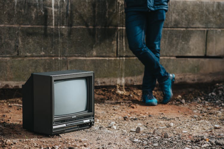 Crop Person Standing Near Fence And Old TV