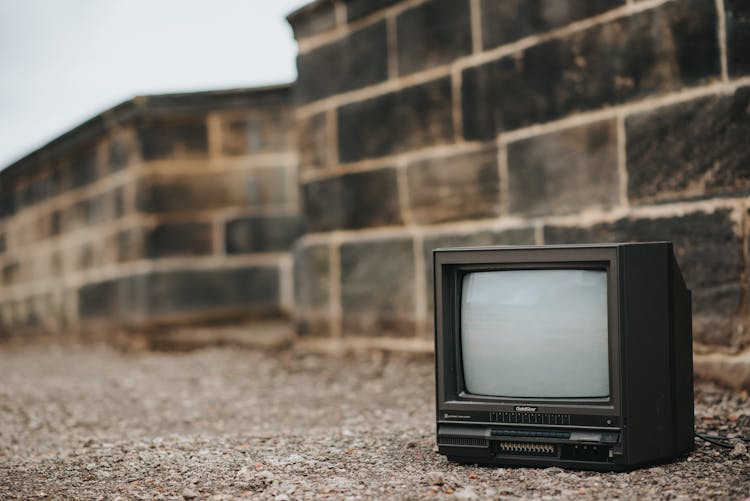 Small Retro TV On Ground Near Stone Barrier