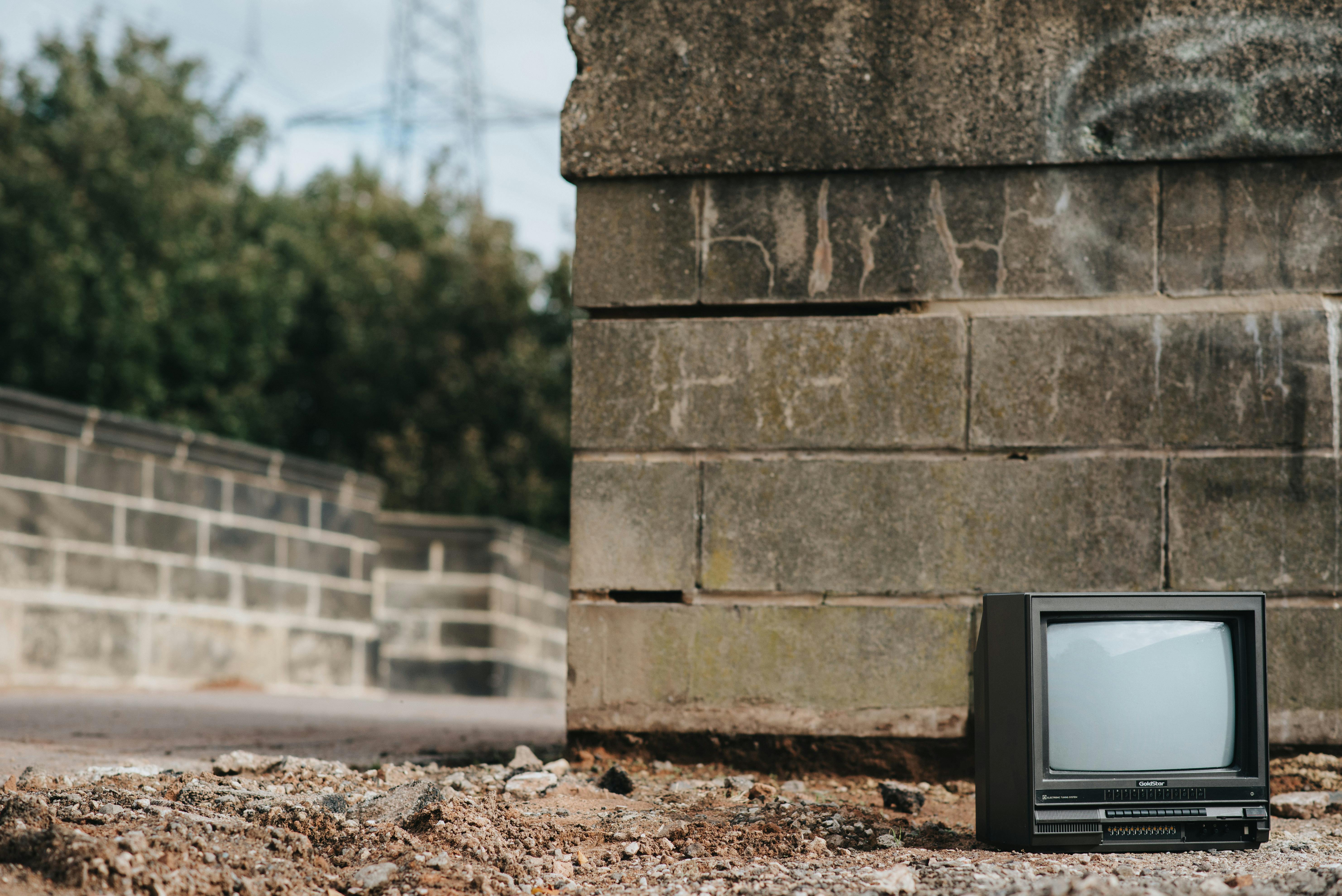 vintage tv set on ground near stone wall