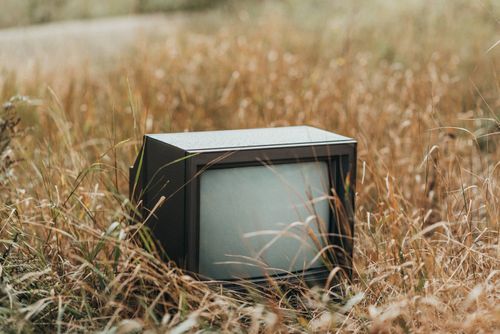 Free Small black obsolete old fashioned television placed on withered dry grass on street against blurred background in countryside in nature Stock Photo