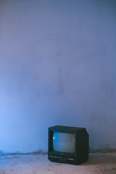 A nostalgic vintage television set against a textured blue wall, ideal for retro themes.