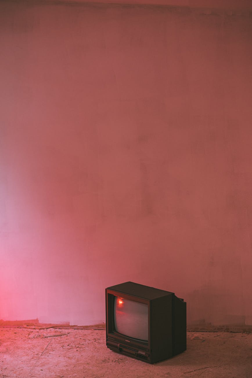 Small retro TV set with plastic case and CRT glass on cement floor near wall in building