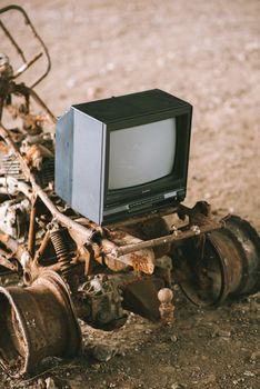 Vintage television set on rusty vehicle on pathway