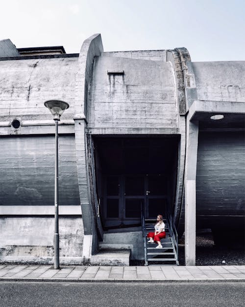 Woman Sitting on Steps of Aerodynamic Park Building in Berlin