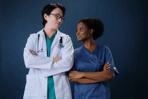 Free Woman in Blue Scrub Suit Standing Beside a Man in White Laboratory Gown  Stock Photo