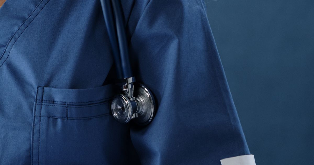 Close-up of a stethoscope resting on a healthcare worker's shoulder.