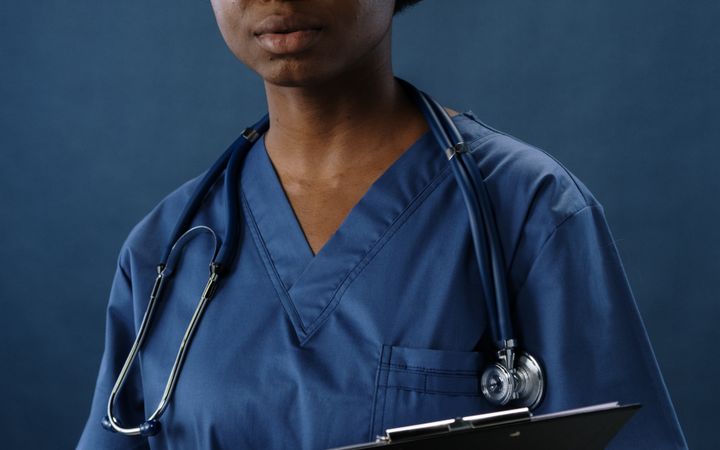 Professional nurse in blue scrubs holding a clipboard, conveying confidence and care.