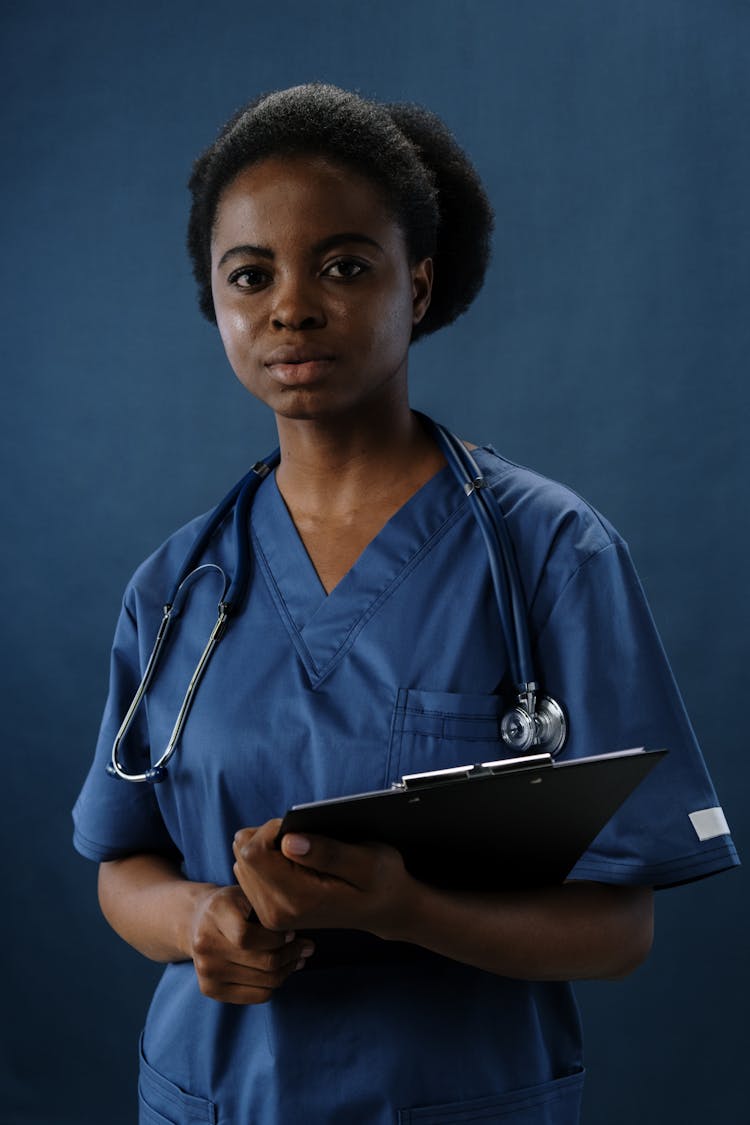 A Woman In Scrubs Holding A Clipboard