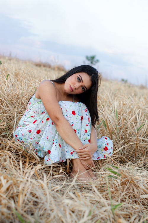 A Beautiful Woman Sitting on Dried Grass