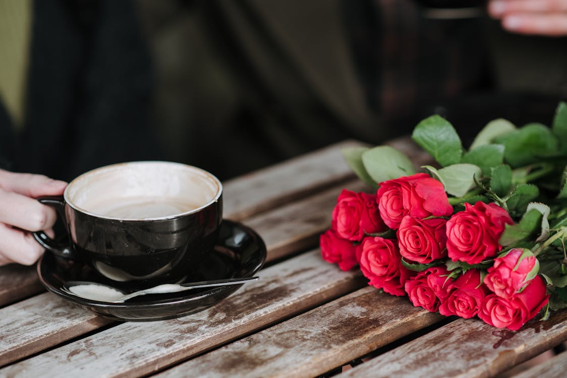 Faceless couple with coffee and rose bouquet in cafeteria · Free Stock ...