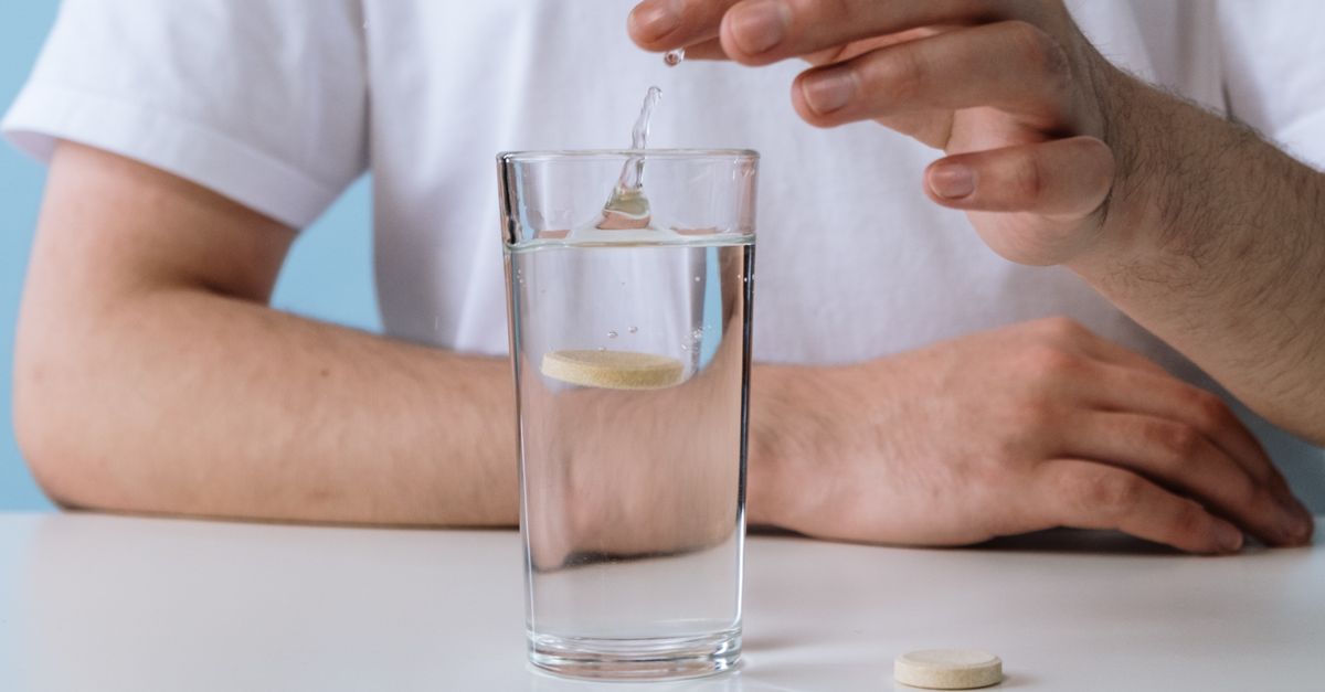 A Person Dropping an Effervescent Tablet into a Glass of Water