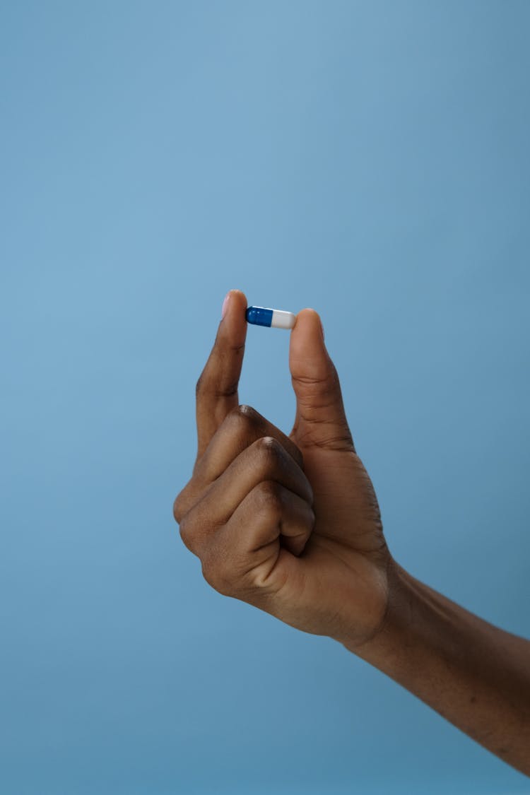 A Person Holding A Blue And White Pill