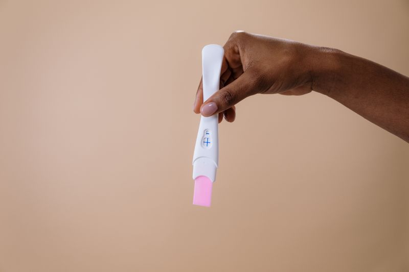 Woman holding pregnancy test with hopeful expression