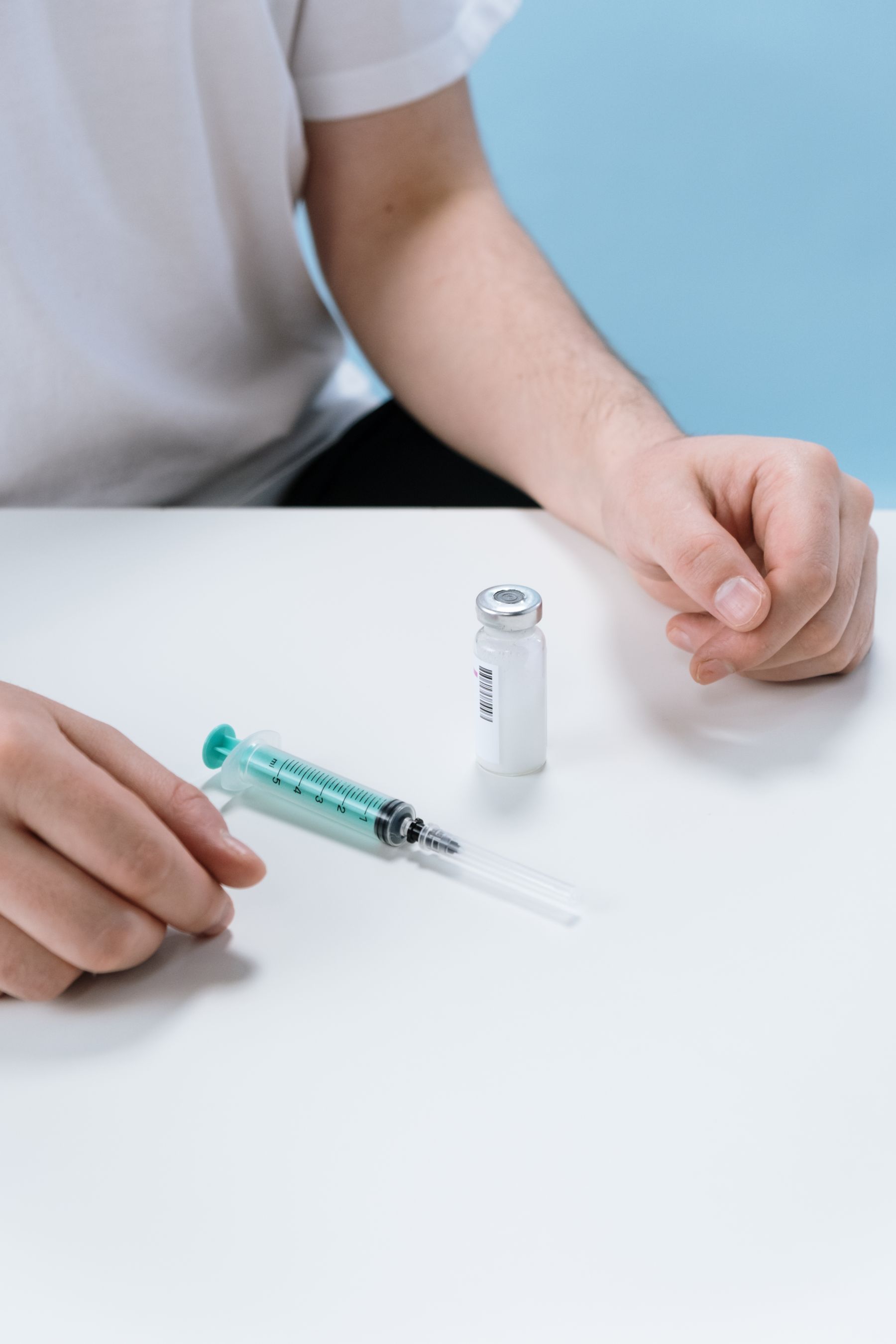 Close-up of gloved hands preparing a syringe and medication vial on a clean surface