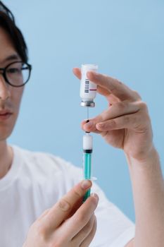 一名男子小心翼翼地将疫苗从小瓶注入注射器