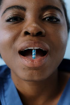 African American woman holds a colorful capsule in her mouth, capturing focus on medication.