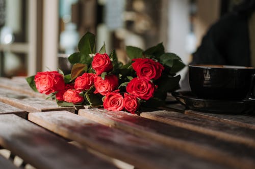 棕色的木桌上的紅玫瑰