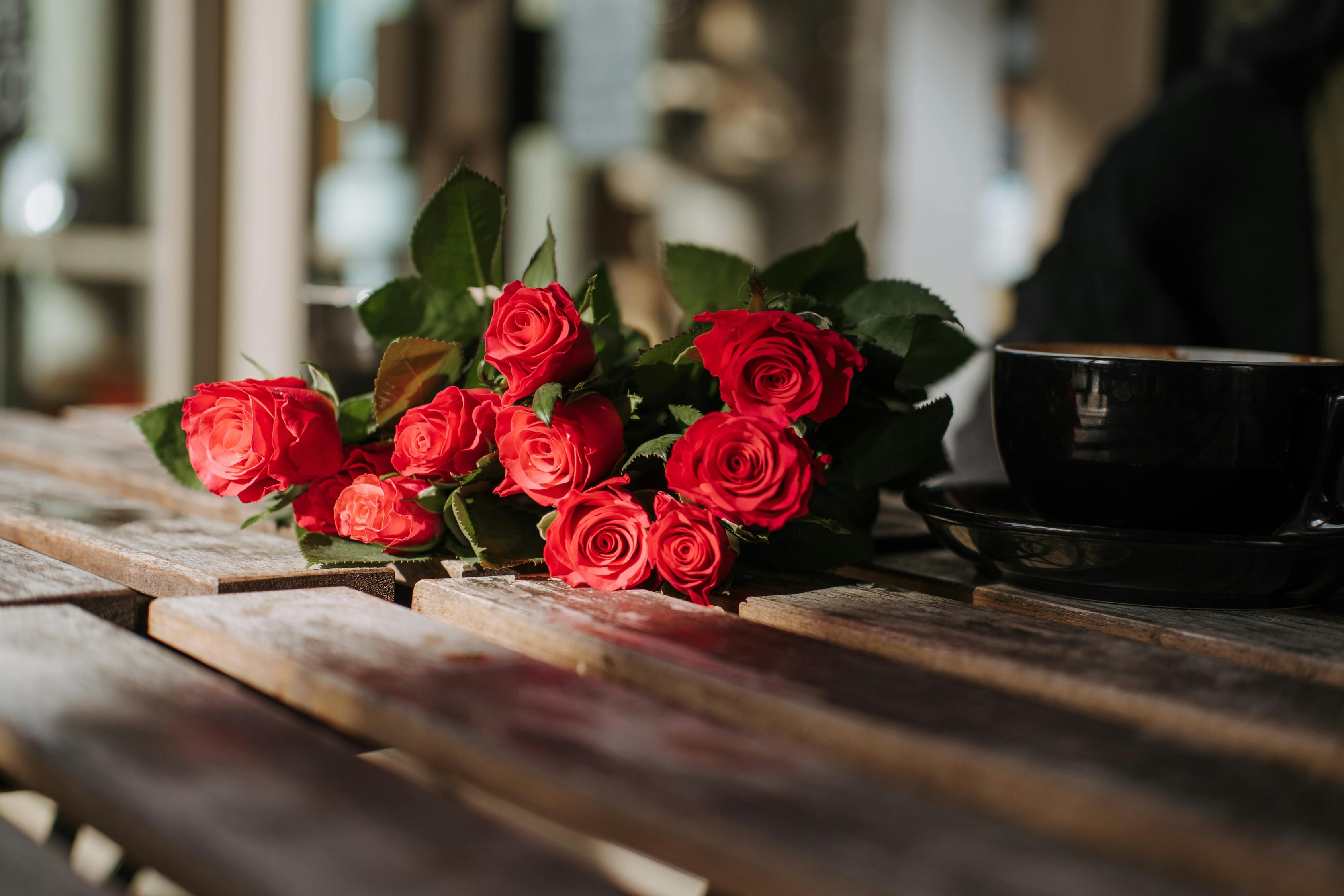 Bright blooming roses near cup of coffee in cafe · Free Stock Photo
