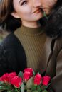 Crop couple with bun ch of roses embracing on street