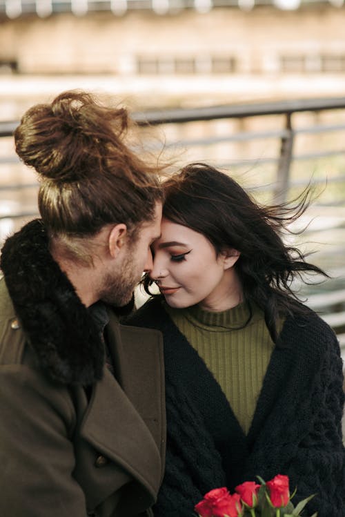 Tender young couple touching foreheads on street