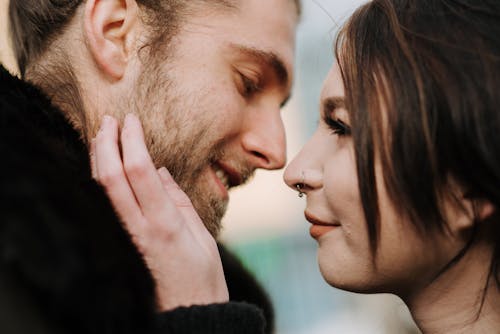 Young woman touching face of smiling boyfriend