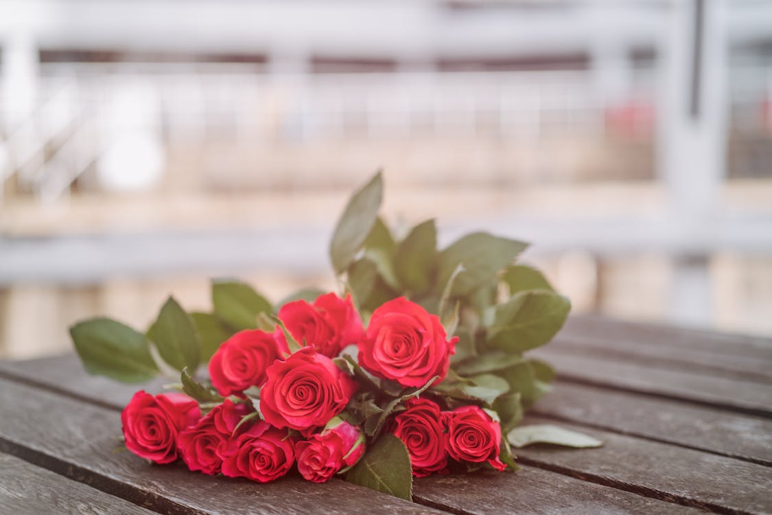 Fragrant roses placed on wooden table on street