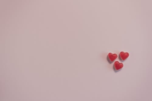 Small red heart shaped candies on pink surface