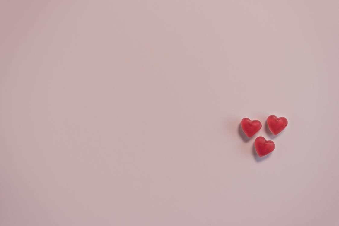Free Small red heart shaped candies on pink surface Stock Photo