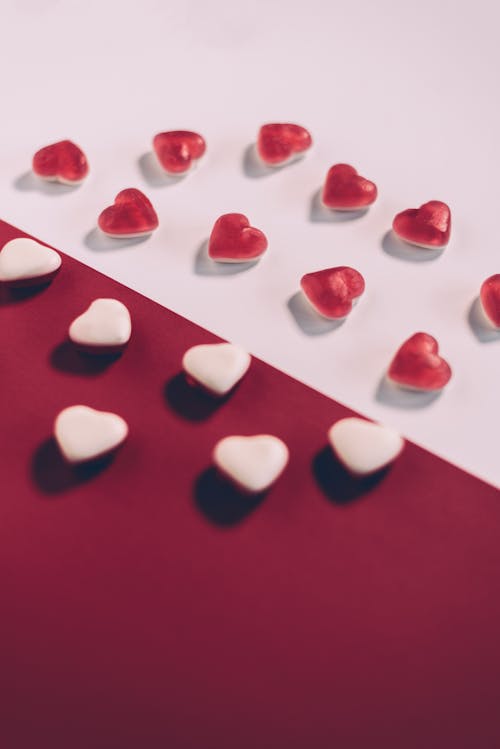 From above arrangement of white and red heart shaped candies placed on multicolored background during saint valentine day celebration in studio