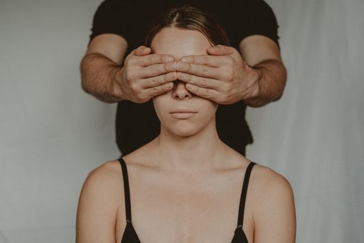 Crop man covering eyes of anonymous woman