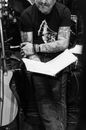 Black and white of crop anonymous man with beard and tattoos repeating song and preparing for rock concert
