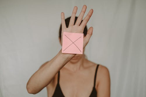 Free Unrecognizable young woman demonstrating prohibition sign showing gesture of refuse using hand and note with sign stop Stock Photo