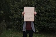 Anonymous female with poster about hurtful love in nature