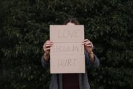 Faceless woman demonstrating in hands poster against abuse