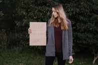 Female demonstrating cardboard with words against abuse