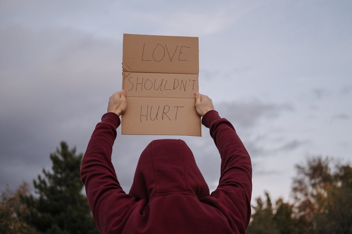 Anonymous activist showing placard with anti violence inscription