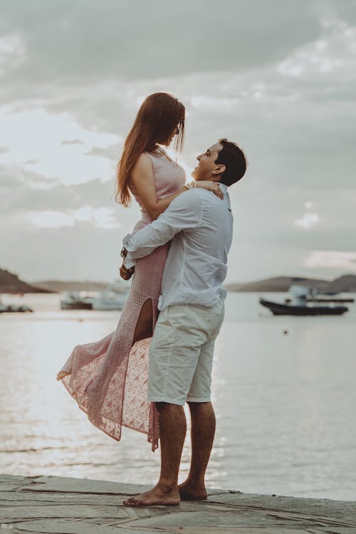 Happy couple standing on pier near sea