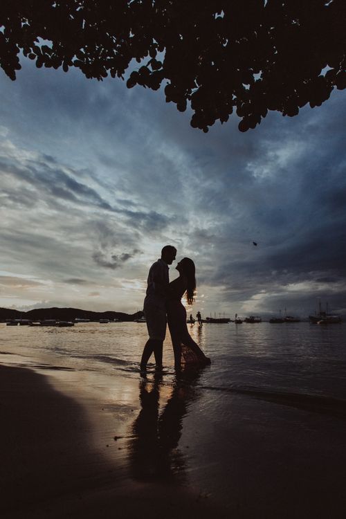 Silhouette of couple standing on sandy beach · Free Stock Photo