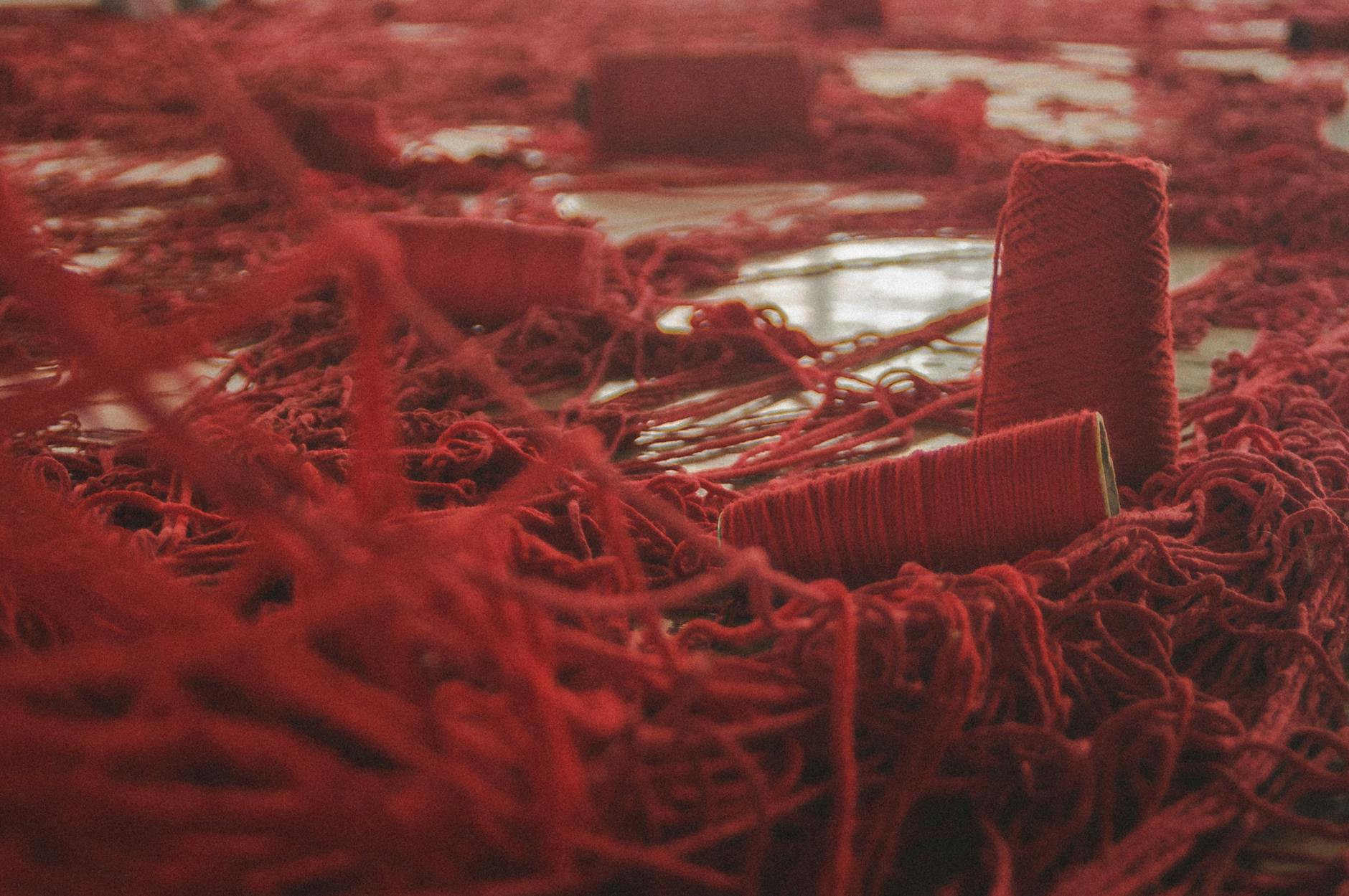 Red sewing thread on spools scattered all over the floor