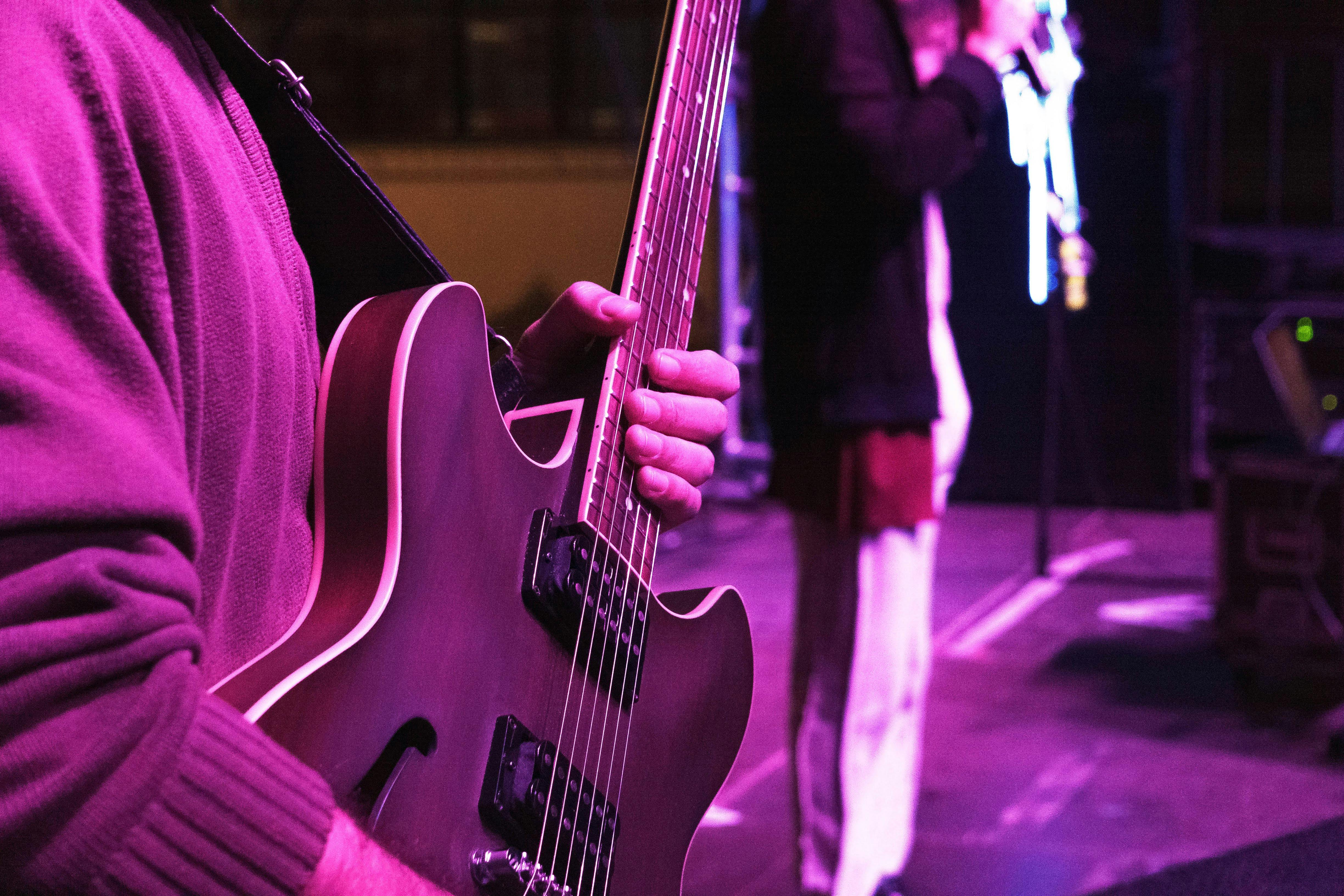 crop guitarist on stage near unrecognizable artist